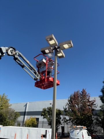 Electrician on a boom lift installing parking lot lights